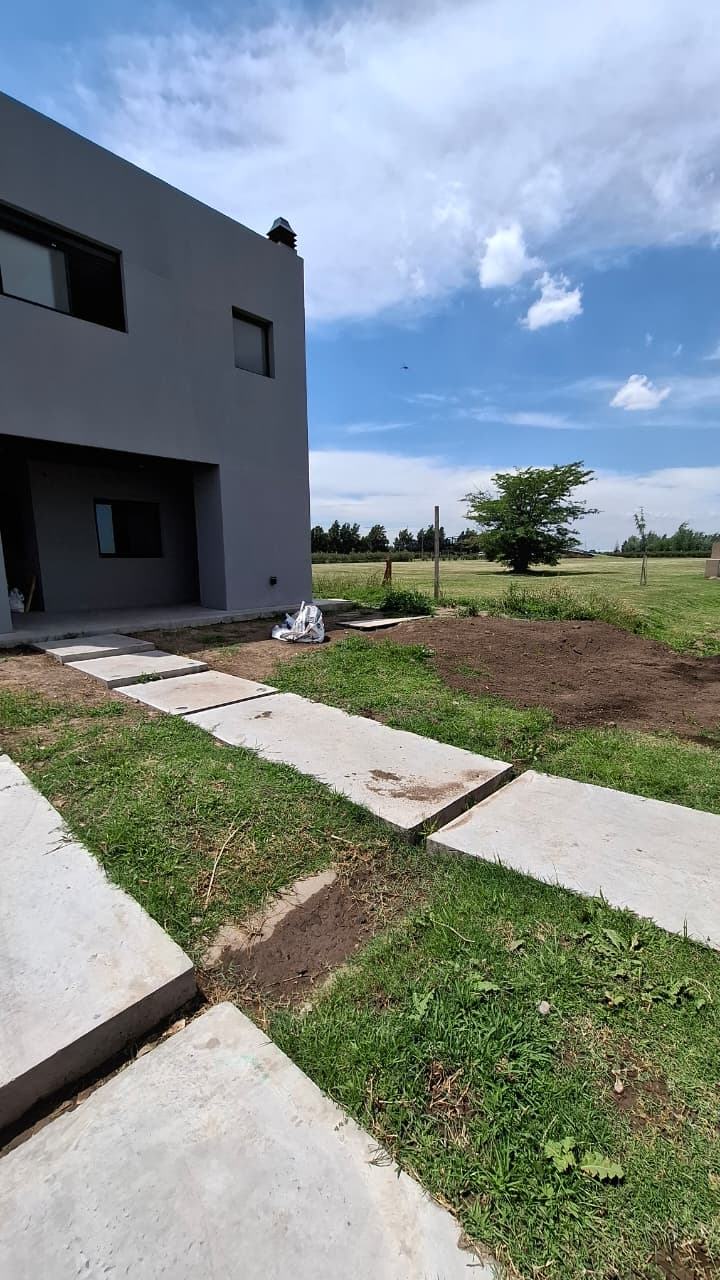 Antes: Sendero lateral · barrio privado en Funes — estado previo a la intervención de jardinería